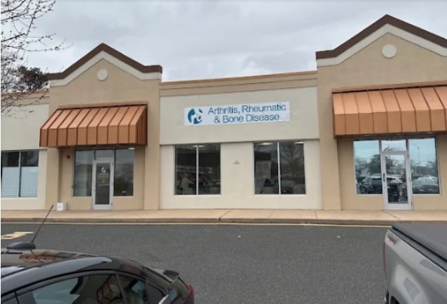 A medical office building with a sign reading 'Arthritis, Rheumatic & Bone Disease' and orange awnings.