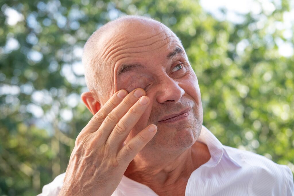 Older gentleman rubbing irritated eye.